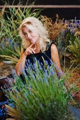 a beautiful middle-aged blonde woman in a black dress in lavender bushes. 