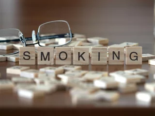 Deurstickers smoking word or concept represented by wooden letter tiles on a wooden table with glasses and a book © lexiconimages