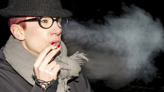 Cinemagraph of young woman standing outside and smokes a cigarette
