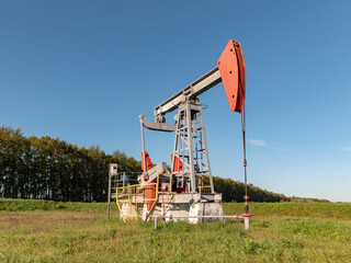 Operating oil and gas well in oil field, profiled against the blue sky