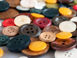 Round sewing buttons of different colours and sizes, close up. Variety of colored flat buttons with two or four holes