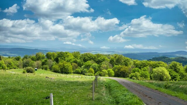 Cinemagraph of meadows and fields with small road and cloudy sky
