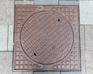 Old rusty sewer hatch on an old metal plate. View from above. - obrazy, fototapety, plakaty
