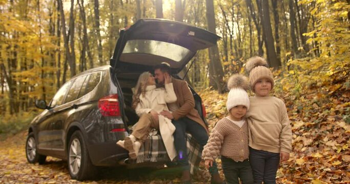 Young family sitting in the trunk of a car in autumn
