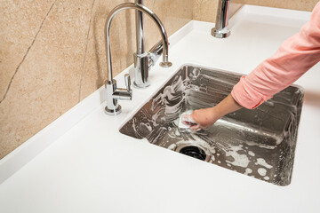 Kitchen sink in foam while washing by female hands