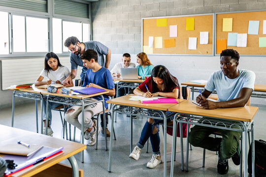 Male Teacher Helping Students In Classroom - Education Concept