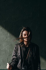 a young girl in a black jacket and torn jeans looks away