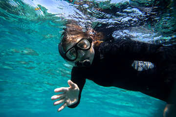 young woman in wet suit snorkling off the coast of Hopkins in Belize - obrazy, fototapety, plakaty