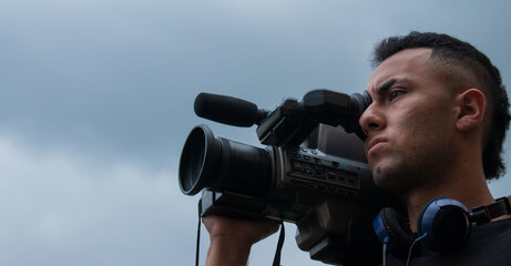 Man filming with a big video camera in a cloudy day