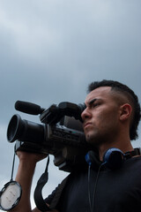 Man filming with a big video camera in a cloudy day