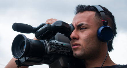 Man filming with a big video camera in a cloudy day