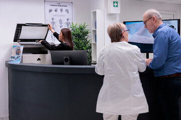 Naklejka premium Worker using copy printer at reception desk to make report papers before checkup consultations. Woman receptionist working on healthcare appointments with forms at registration counter.