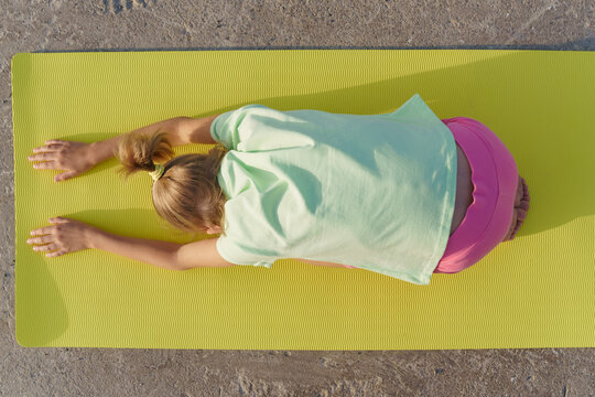 A girl doing yoga on a yoga mat, top view.