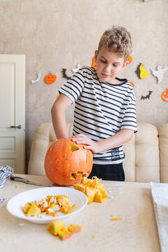 A boy is cutting a pumpkin Jack o lantern for Halloween.