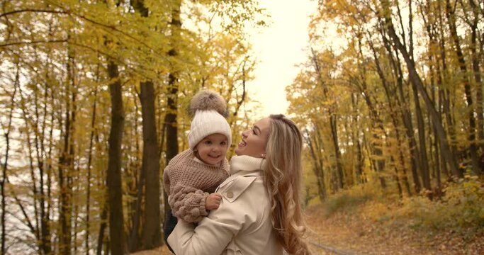Young mother with her daughter in the autumn park