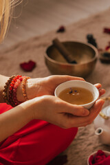 Woman sit on the floor and drink tea from herbs and flowers. Tea ceremony during relaxation harmony