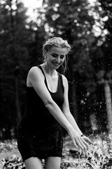 Happy woman having fun at the city fountain on a summer day.