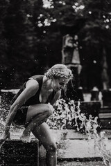 Happy woman having fun at the city fountain on a summer day.