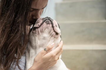 Young latin woman caresses and hugs her dog (french bulldog) next to the stairs