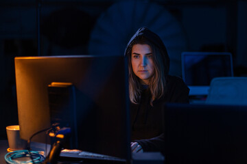 cybercrime, hacking and technology concept - female hacker in dark room writing code or using...
