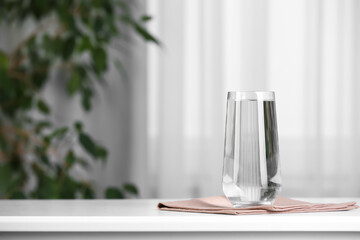 Glass of pure water on white table indoors, space for text