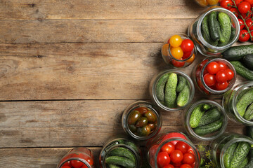 Pickling jars with fresh vegetables on wooden table, flat lay. Space for text