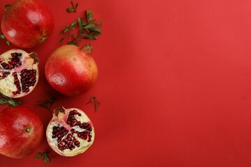 Flat lay composition with ripe pomegranates on red background. Space for text