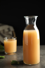 Fresh pear juice in glass bottle on grey table