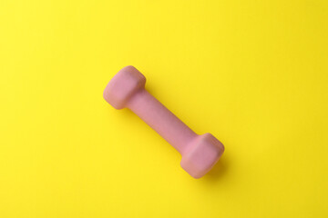 Stylish dumbbell on yellow background, top view