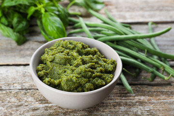 Bowl with tasty puree, green beans and basil on wooden table, closeup