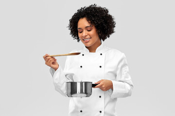 culinary and people concept - happy smiling female chef in jacket with saucepan cooking food over...
