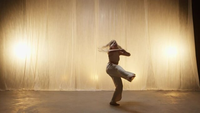 Silhouette of a Professional Dancer Performing in Studio in Soft Warm Lighting