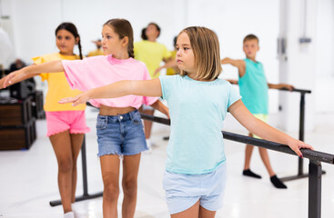 Youth girls and boys training ballet moves in studio. High quality photo