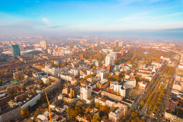 Aerial view camera flight above the autumn city in foggy weather with many buildings and roads and highways. Weather. Cloudy. Modern. Scenic. Vegetation. Autumn Forest. October. Leaf. Park. Landmark
