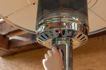 Female hand is shutting down  Gas Air Heater.  Gas consumption concept.