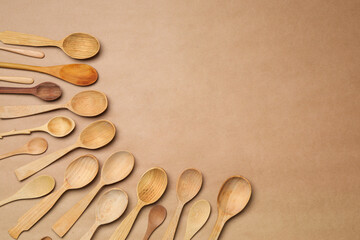 New wooden spoons on brown background, flat lay with space for text. Cooking utensils