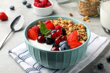 Bowl with tasty granola and berries on light grey table. Healthy meal