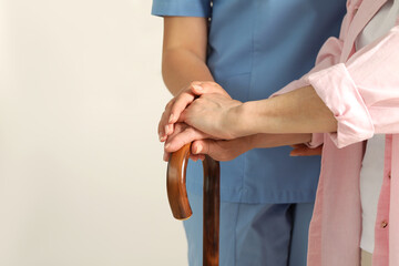 Elderly woman with walking cane and female caregiver indoors, closeup. Space for text