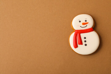 Christmas snowman shaped gingerbread cookie on brown background, top view. Space for text