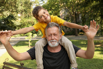 Senior man with his little grandson having fun together in park