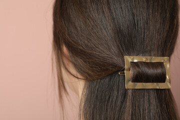 Young woman with beautiful gold hair clip on pink background, closeup