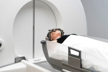 The patient lies in front of the device for the treatment of cancer with a gamma knife. She has a...