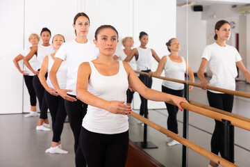 Group of women standing in row together while doing ballet dance moves.