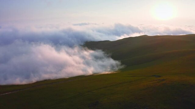Clouds And Fog Creeping Over Mountain Valley At Sunset, Aerial View From Drone