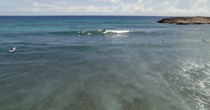 Aerial view of surfers, riding waves on the coast of Isabela, Puerto Rico, USA - tracking, drone shot