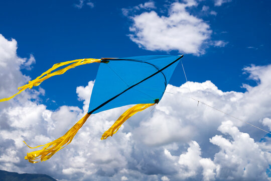 A blue and yellow kite flying against a sky