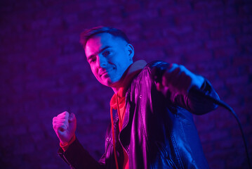 A man singer with the microphone in the neon lights concept.