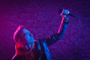 A man singer with the microphone in the neon lights concept.