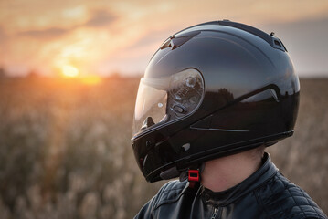 Biker in the helmet in the sunset rays close up portrait.