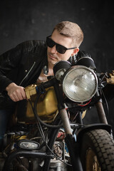 A motorcyclist in the black leather jacket and sunglasses on the old motorbike.